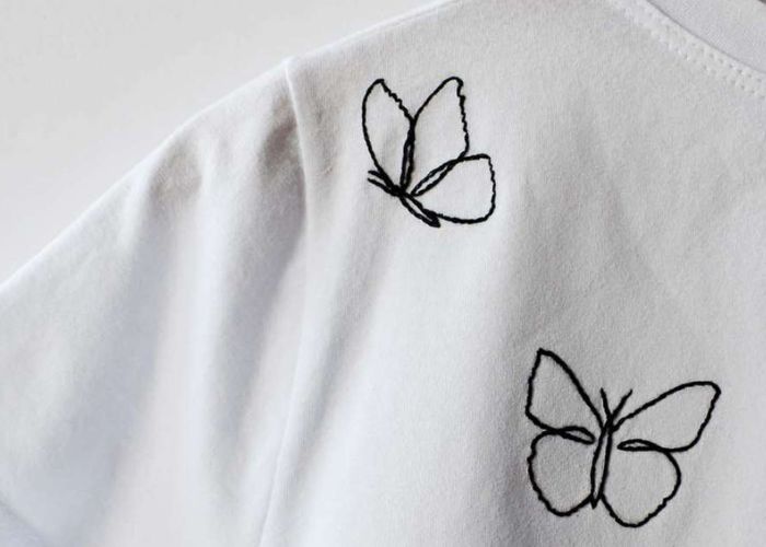 Idée de raccommodage : Contours de papillons noirs brodés sur un t-shirt blanc
